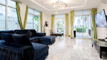 A modern living room with a sofa set, a dining table, and a TV.