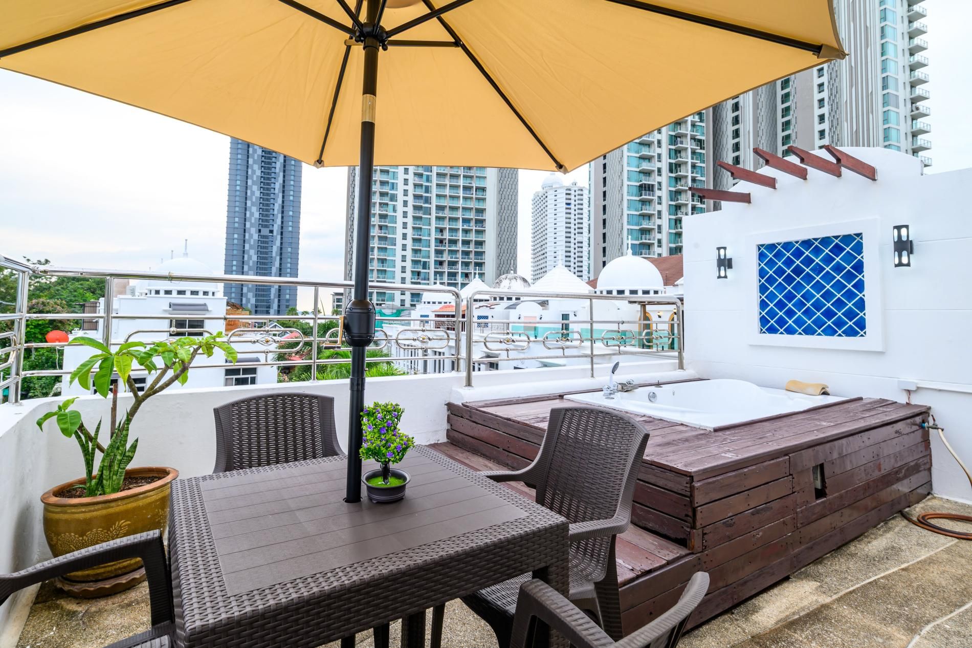 Eine Dachterrasse mit Tisch, Stühlen, einem Whirlpool und Kübelpflanzen.