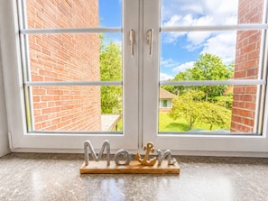 Ein Fenster mit Blick auf ein Backsteingebäude und einen Baum.