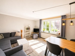 A modern living room with a sofa, a dining table, and a TV. - Holiday Apartment With 1 Bedroom (Wyk auf Foehr)