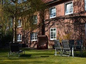 A brick building with multiple windows, a lawn, and outdoor seating. - Holiday Apartment With 1 Bedroom (Wyk auf Foehr)