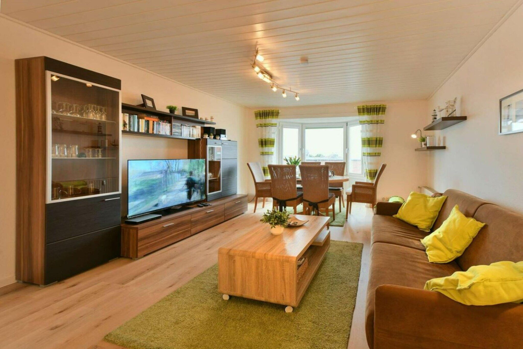 Un salon équipé d’un téléviseur, de meubles en bois, d’un canapé et d’un coin repas.