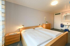A hotel room with a double bed, bedside tables, a small wooden cabinet, a mirror, and a sink. - Apartment 17 in Wangerooge (Wangerooge)