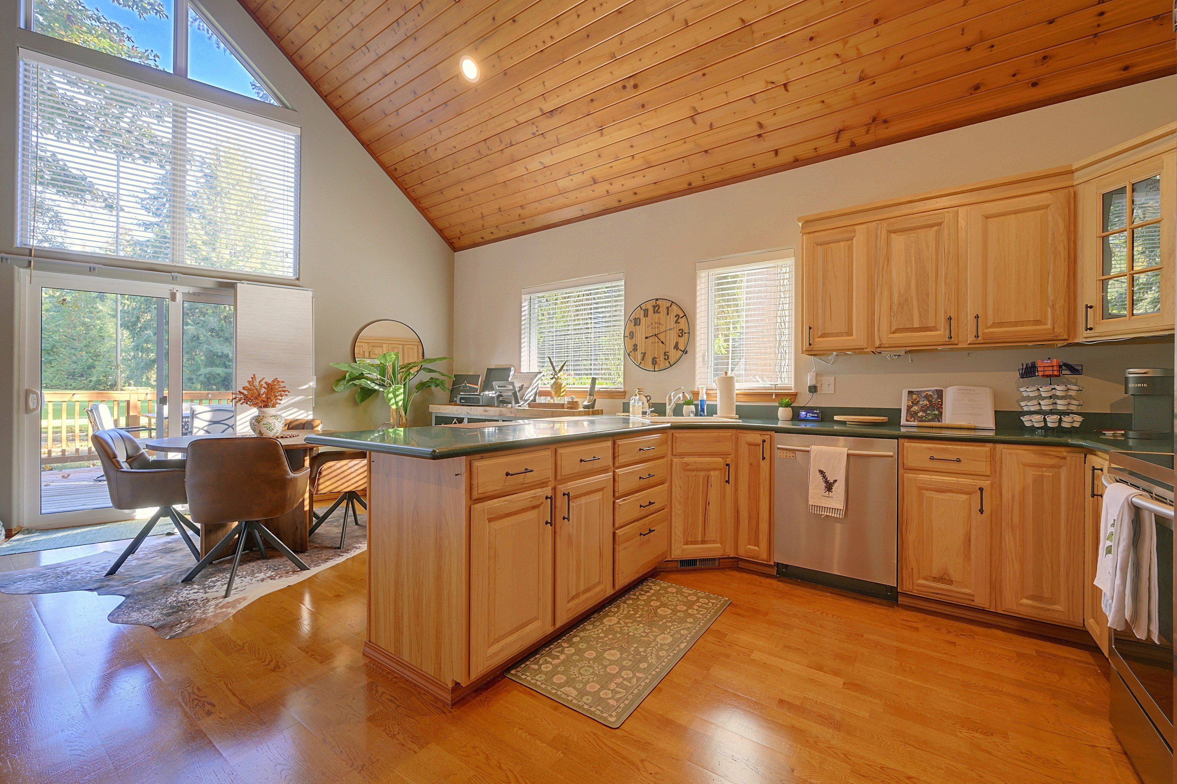 Una cocina con armarios de madera, un comedor con mesa y sillas, y ventanas amplias.
