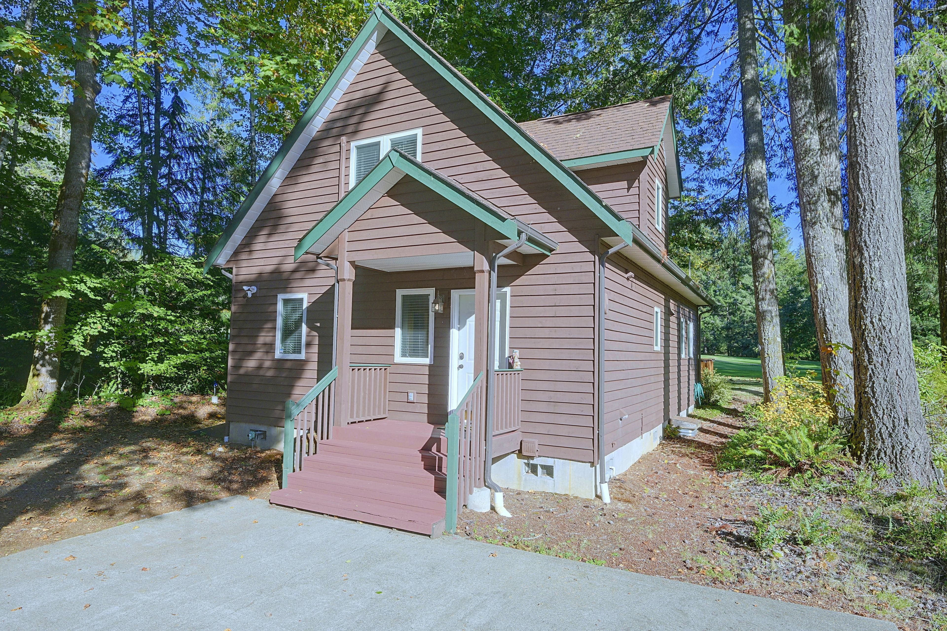 A small, single-story building with a brown exterior and green trim, surrounded by trees.