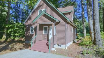 A small, single-story building with a brown exterior and green trim, surrounded by trees.