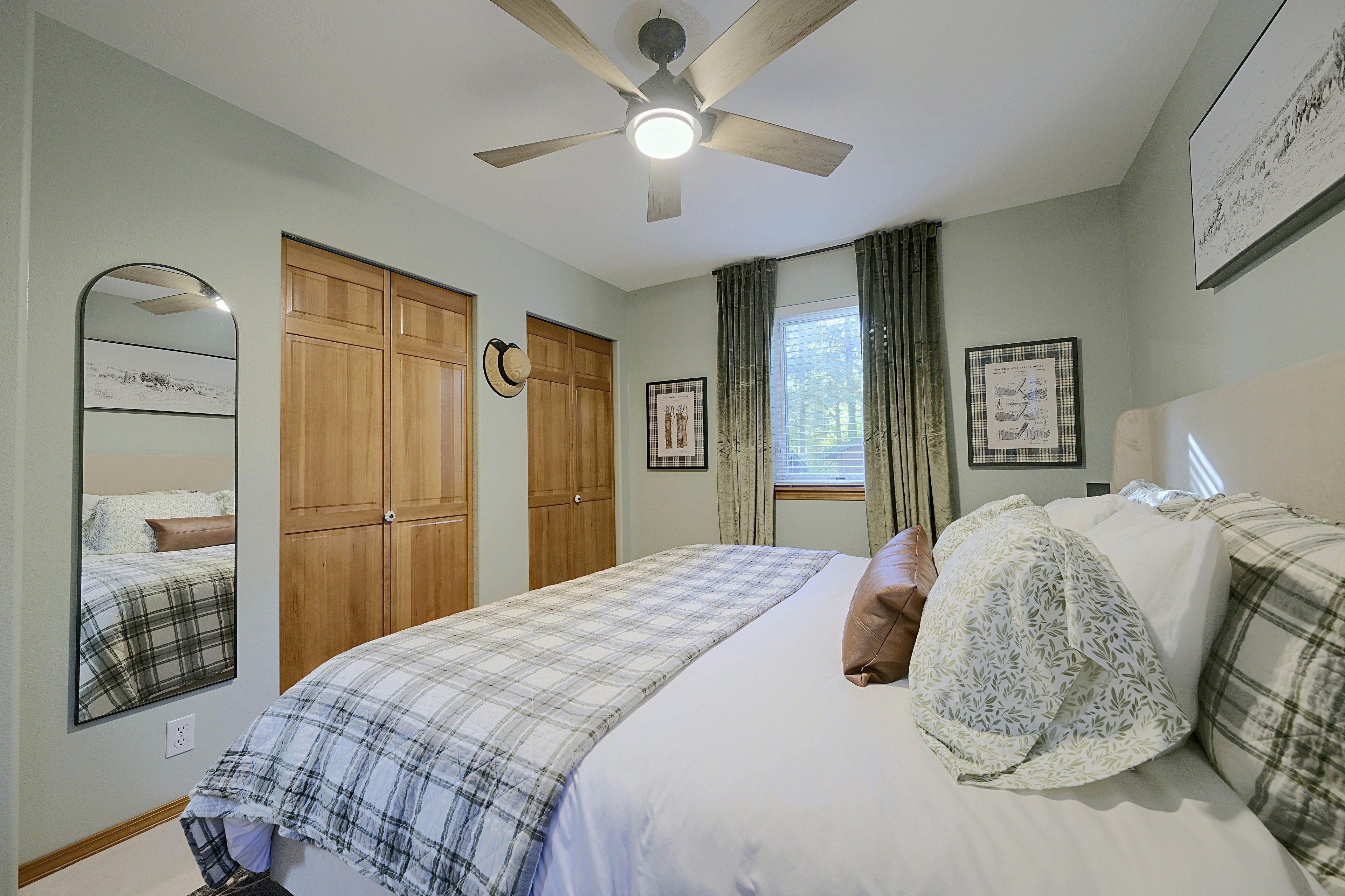 A bedroom with a bed, a ceiling fan, a wardrobe, and a window with curtains.