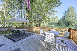 Une terrasse en bois avec une table et des chaises, un drapeau américain et une vue sur un terrain de golf.