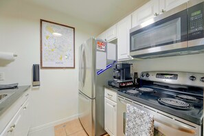A kitchen with a refrigerator, microwave, stove, and a coffee maker. - Walkable West 6th Condo w/ Pool & Porch (Austin)