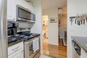 A kitchen with a microwave, coffee maker, stove, and a set of knives on the wall. - Walkable West 6th Condo w/ Pool & Porch (Austin)