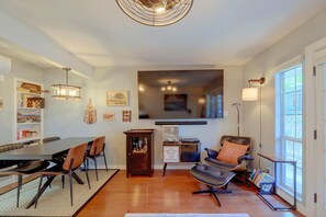 A dining area with a table and chairs, a bookshelf, and a television mounted on the wall. - Walkable West 6th Condo w/ Pool & Porch (Austin)