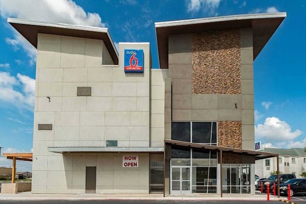 A modern building with a 'NOW OPEN' sign, a 'studio 6' sign, and a stone-textured facade. - 1 King Bed|NS| Kitchen (New Braunfels)