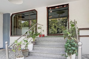 A staircase with potted plants leading to a door with a window. - Collection O Tourist Complex Area (Agra)