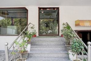 A staircase leading to a door with a glass panel, flanked by potted plants and a metal railing. - Collection O Tourist Complex Area (Agra)