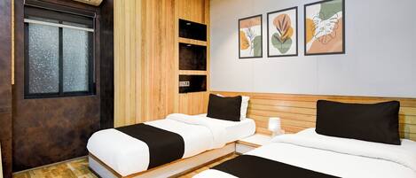A hotel room with two beds, a wooden ceiling, and artwork on the wall.