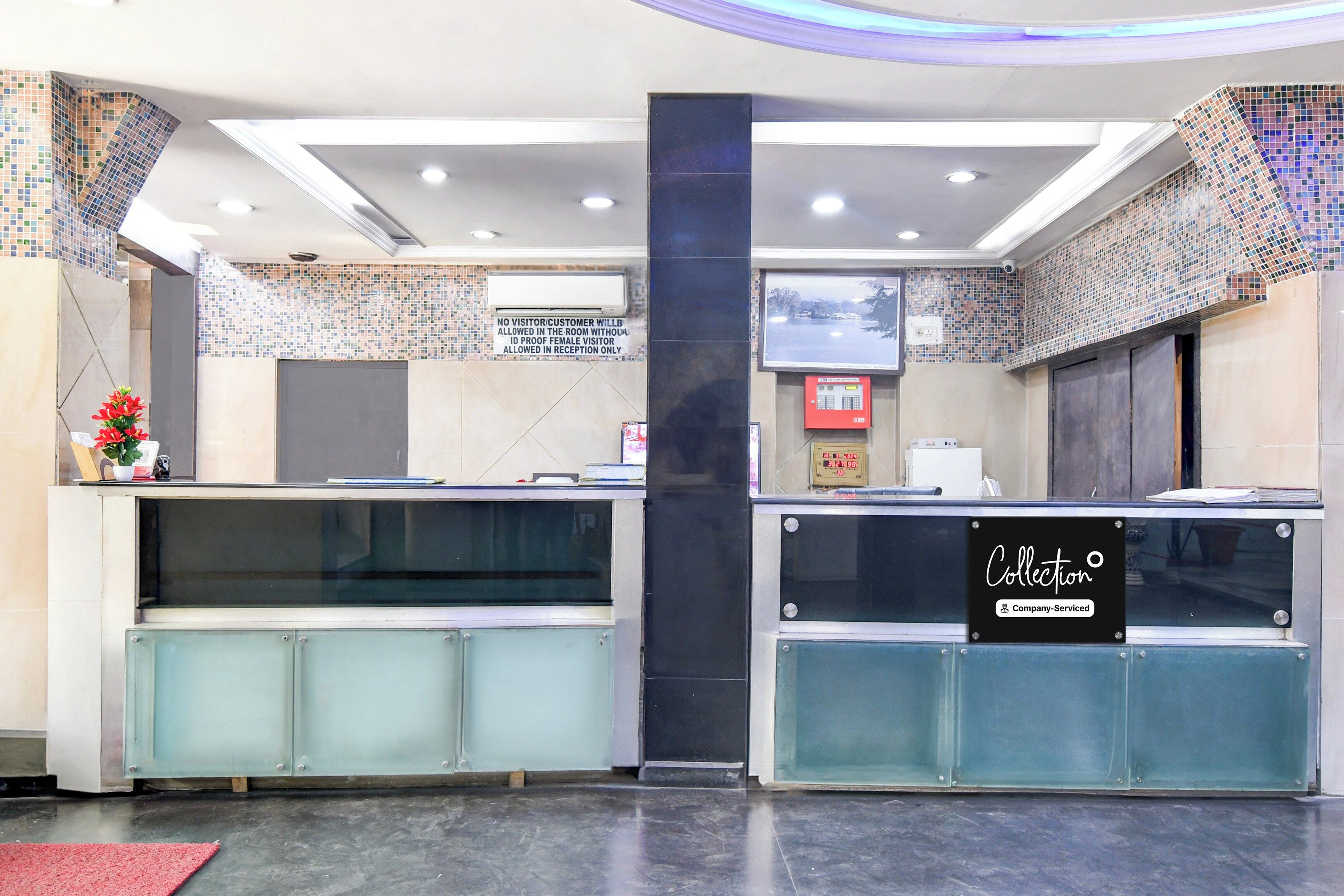 A reception area with a glass partition, a digital display, and a sign indicating the space is company-serviced.