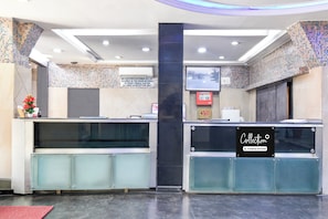 Un área de recepción con separador de vidrio, pantalla digital y letrero que indica que el espacio es de servicio de la empresa.