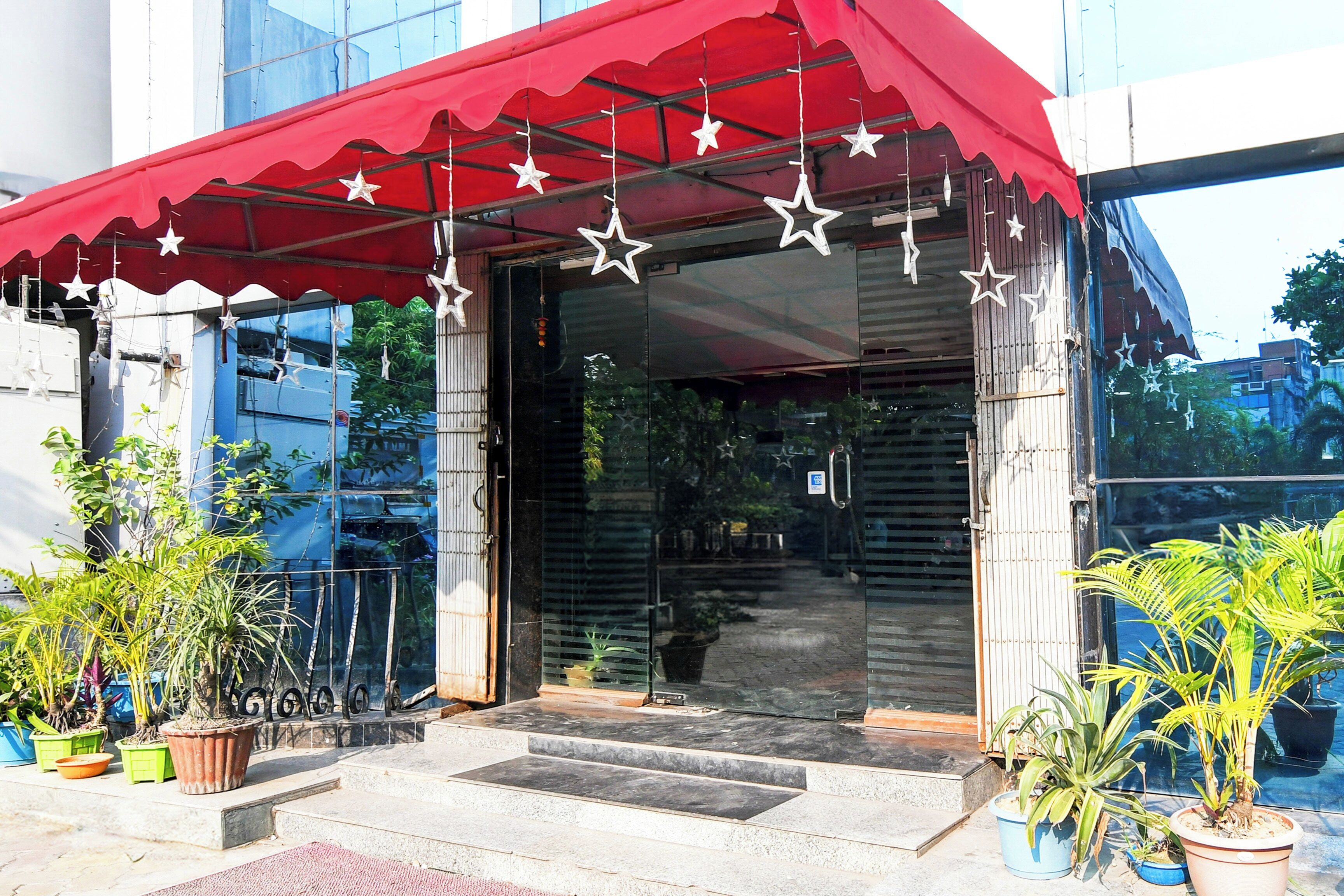 A building entrance with a red awning, star decorations, and potted plants.