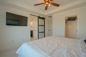 A bedroom with a bed, a ceiling fan, a TV mounted on the wall, and a door leading to a bathroom. - Spacious & Modern Springs Home w/ Mtn Views (Colorado Springs)