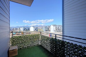 A balcony with a view of a residential area, a construction site, and mountains in the distance. - Spacious & Modern Springs Home w/ Mtn Views (Colorado Springs)