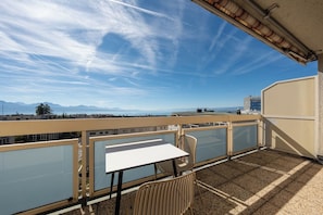 A balcony with a table and chairs, overlooking a cityscape with mountains in the distance. - Spectacular lake view •Balcony • 7th floor (Lausanne)