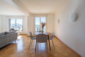 Uma sala de estar moderna com área de jantar, janelas amplas e vista para o mar.