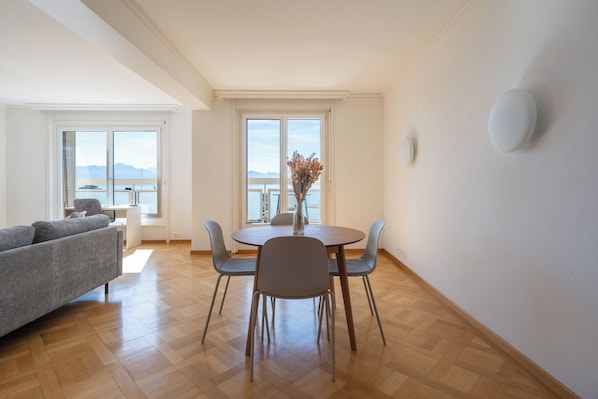 A modern living room with a dining area, large windows, and a view of the sea. - Spectacular lake view •Balcony • 7th floor (Lausanne)