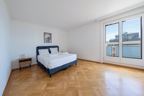 Quarto com cama, mesa de cabeceira, janela e porta.