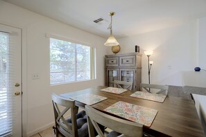 A dining area with a wooden table, four chairs, a globe on a cabinet, and a lamp. - Extended Stay Ready! Sparkis Townhome w/ Patio (Sparks)