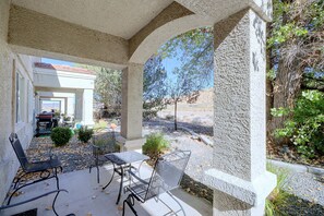 Eine Außenpatio mit Steinpfeilern, Metallstühlen und Blick auf die umliegende Landschaft.