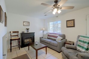 A living room with a fireplace, a ceiling fan, a window with a view, and a couch with a blanket. - Extended Stay Ready! Sparkis Townhome w/ Patio (Sparks)