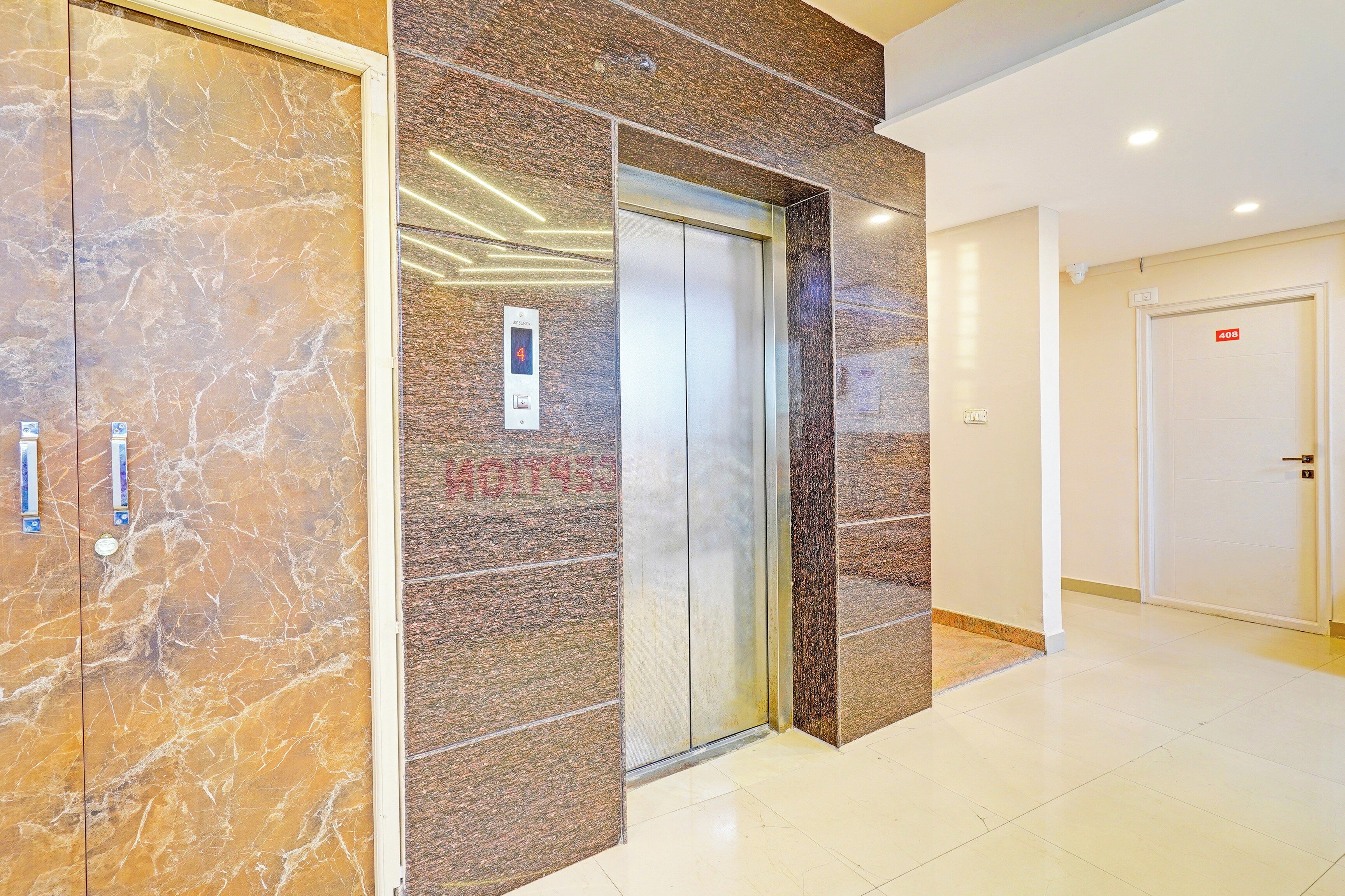 An elevator in a hallway with marble walls and a door marked with the number 408.