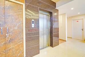 An elevator in a hallway with marble walls and a door marked with the number 408. - Hotel O Indian Suites (Bangalore)