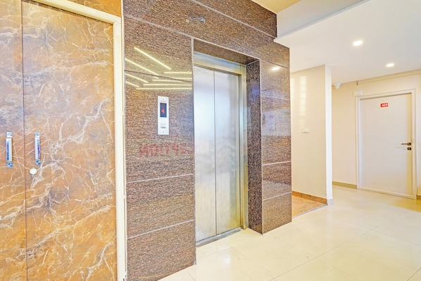 An elevator in a hallway with marble walls and a door marked with the number 408.