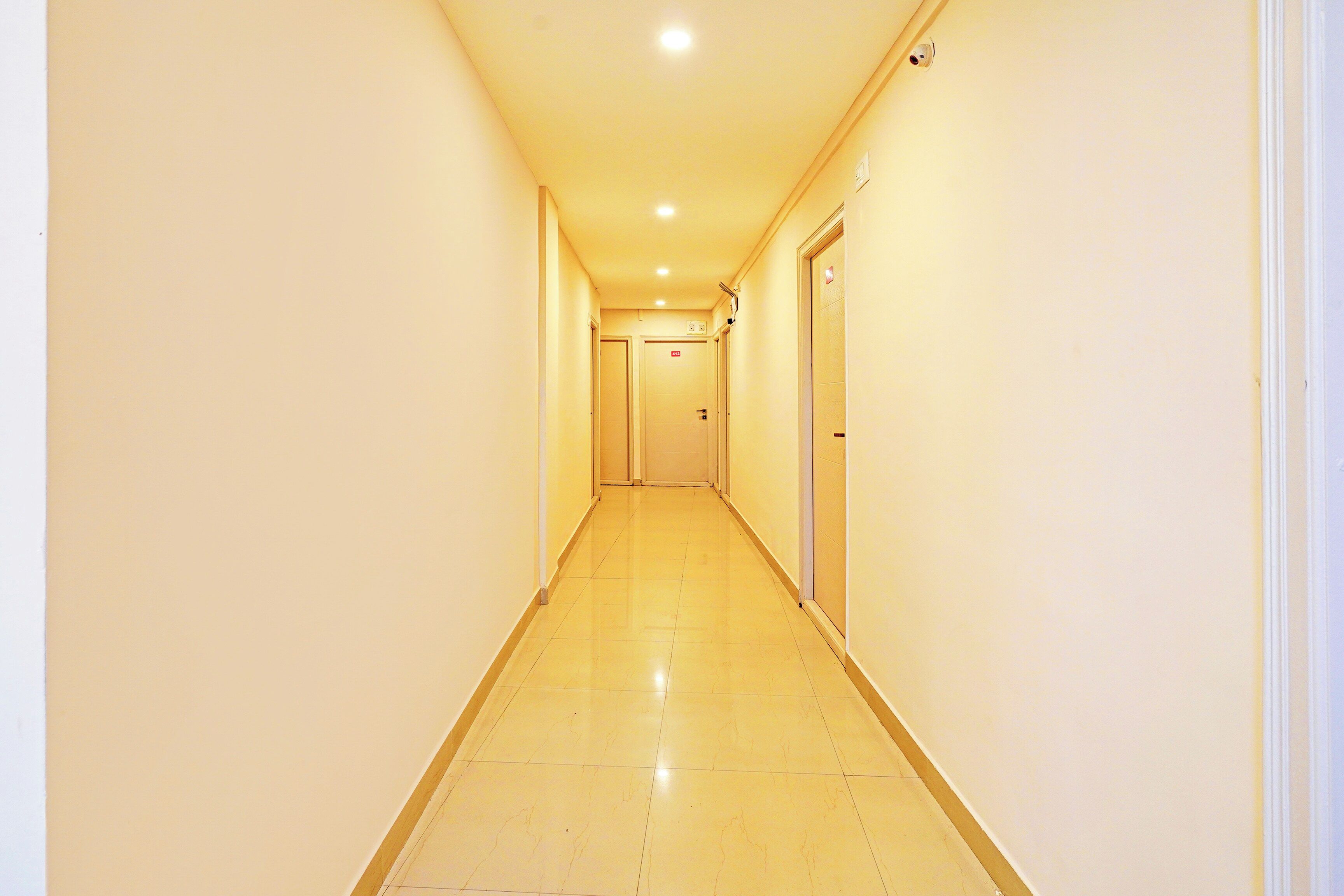 A long, narrow hotel corridor with doors on both sides and a tiled floor.