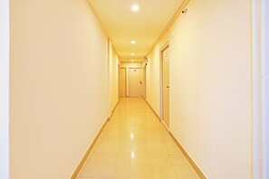 A long, narrow hotel corridor with doors on both sides and a tiled floor.