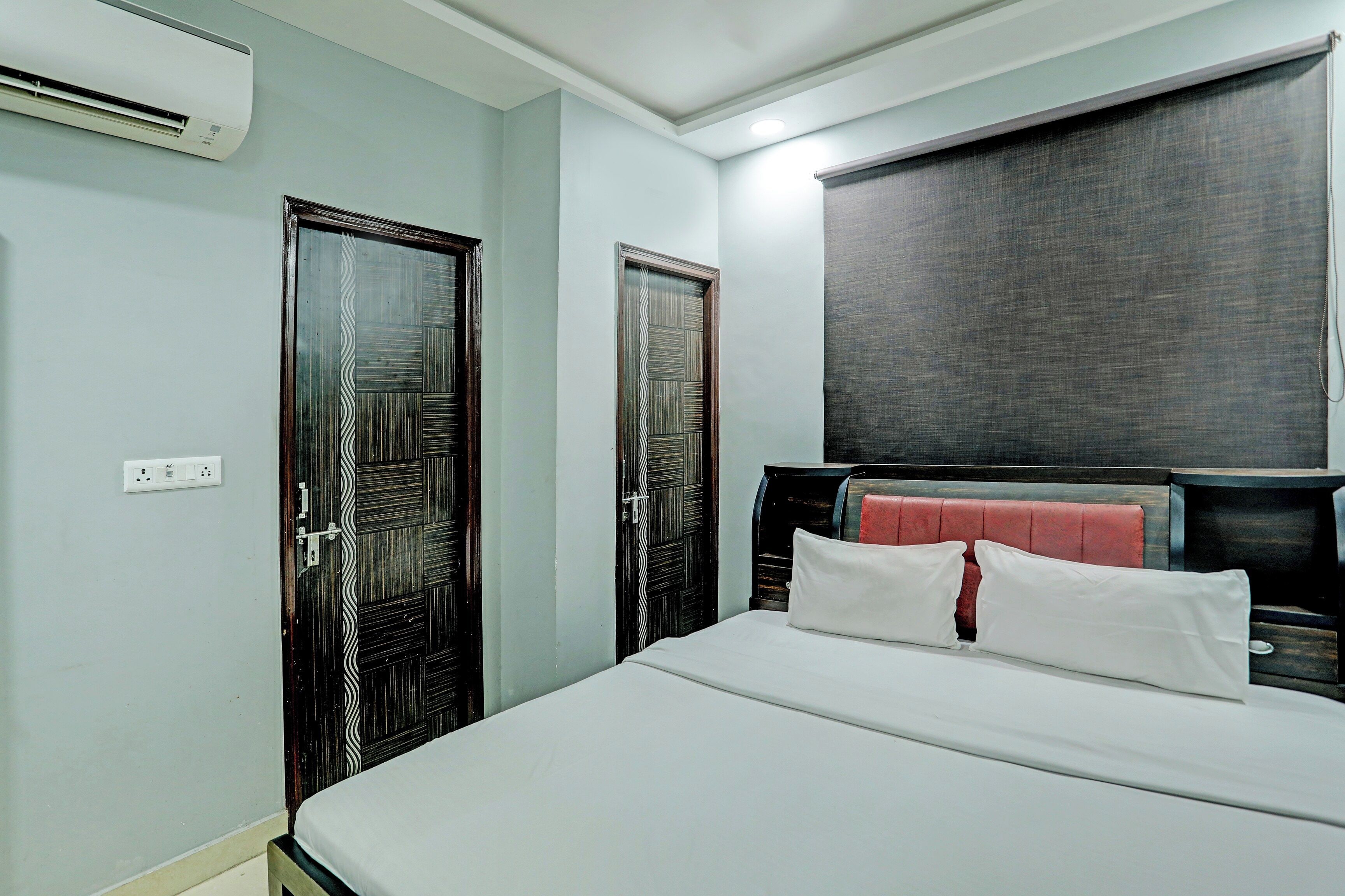 Habitación de hotel con una cama, armario, espejo y equipo de aire acondicionado.