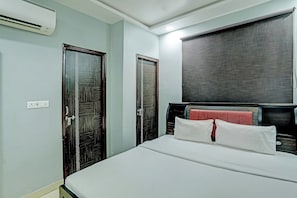 A hotel room with a bed, a wardrobe, a mirror, and an air conditioning unit. - Hotel O Solam Inn (Lucknow)