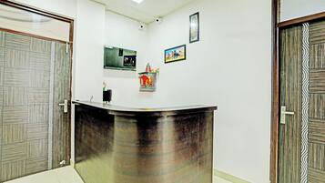 Un mostrador de recepción con superficie de vidrio, dos cámaras de seguridad y un cuadro en la pared.