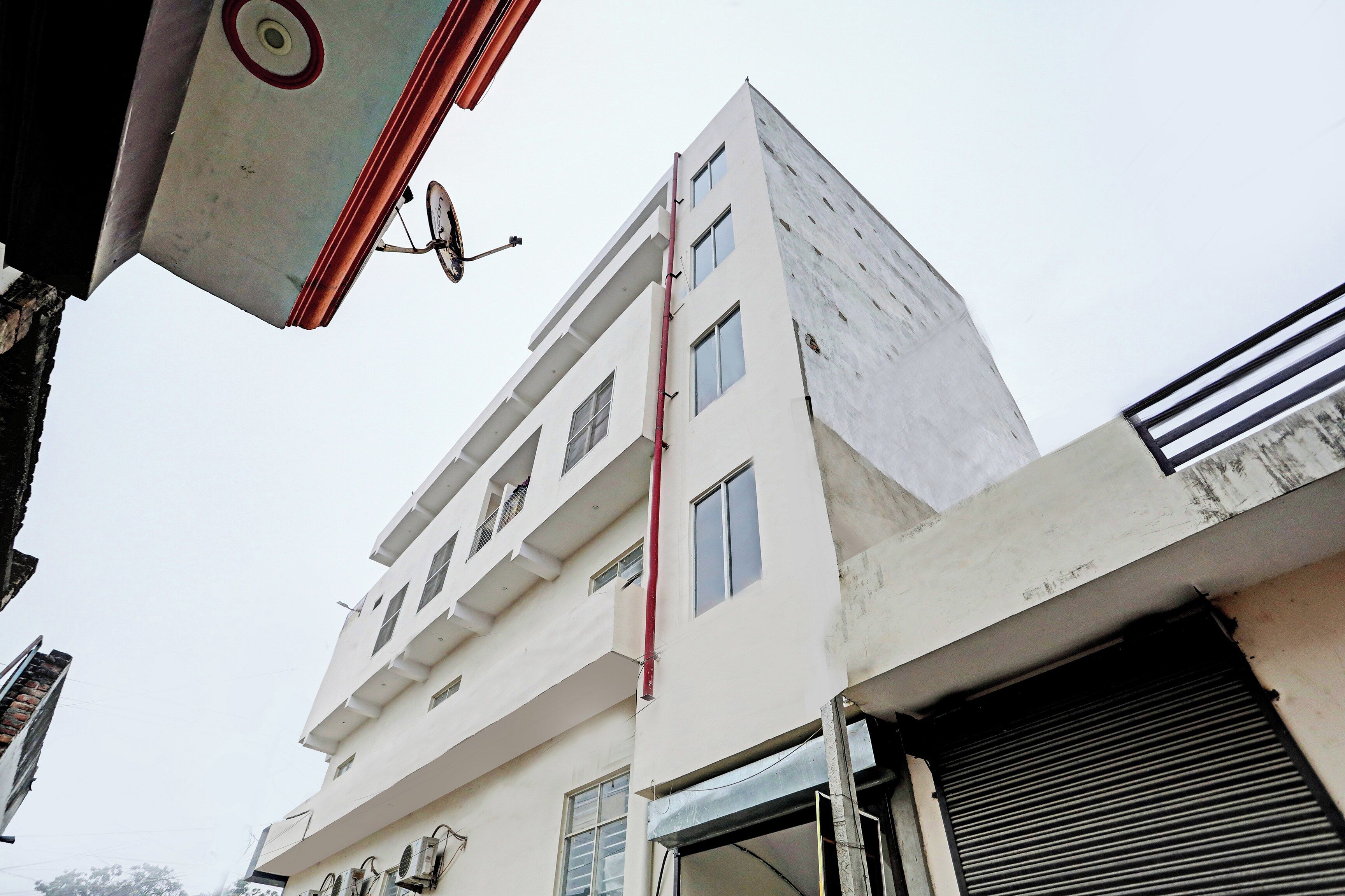 Un edificio de varios pisos con fachada plana, múltiples ventanas y una entrada visible con una reja metálica.