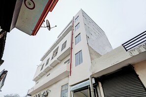 Un edificio de varios pisos con fachada plana, múltiples ventanas y una entrada visible con una reja metálica.