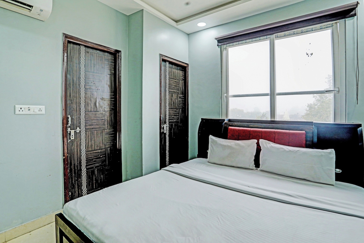 A bedroom with a bed, two doors, a window, and a power outlet.
