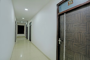 A hallway with a tiled floor, a door with a decorative panel, and a ceiling with recessed lighting. - Hotel O Solam Inn (Lucknow)