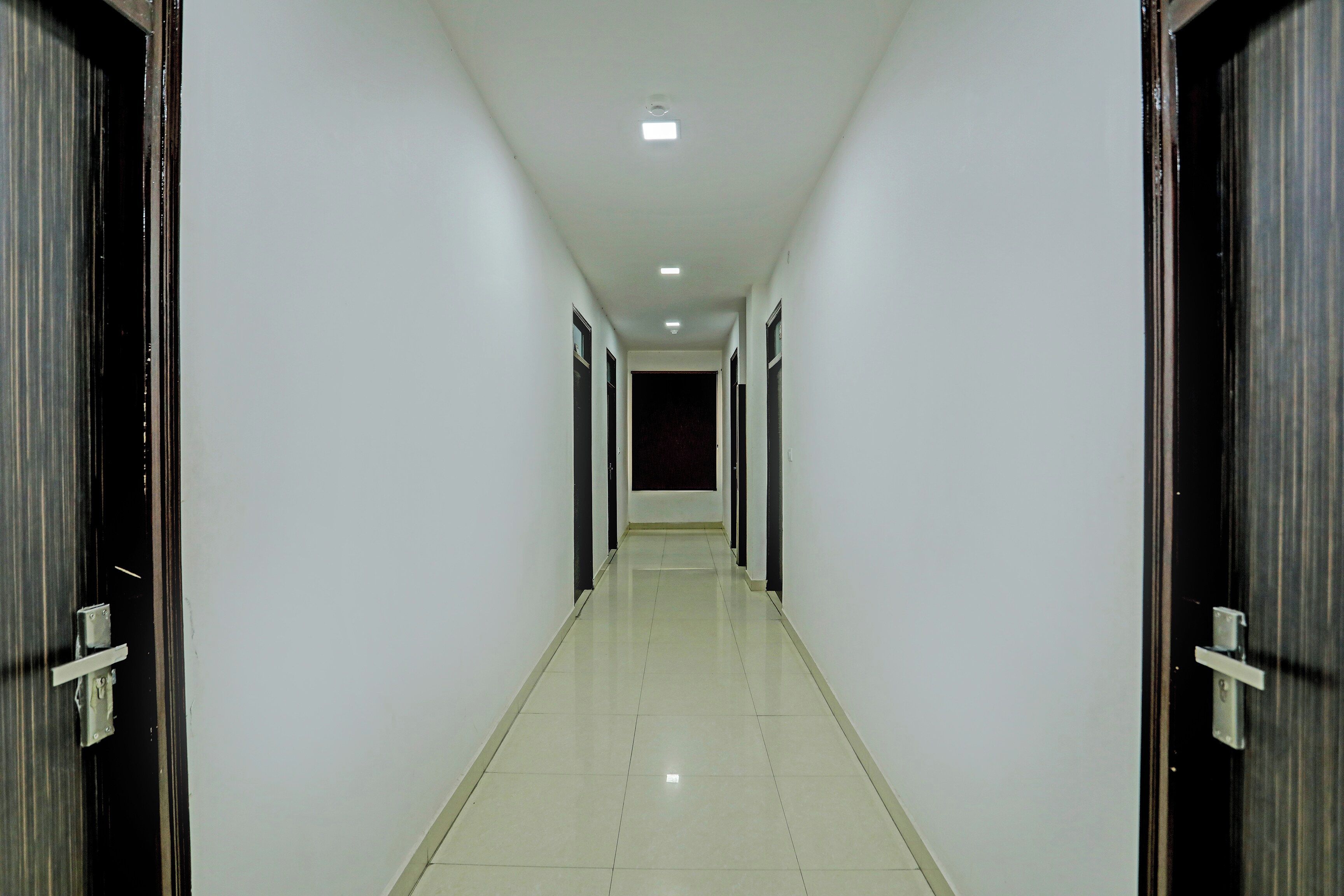 Un pasillo con puertas a ambos lados que conduce a una habitación oscura al final.