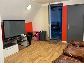 A room with a television, a sofa, a door, and a hallway leading to another room. - New Listing (Les Avenières Veyrins-Thuellin)
