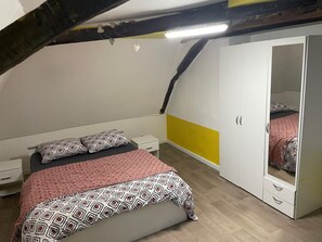 Ein Schlafzimmer mit Bett, Nachttischen, einem Kleiderschrank und einem Spiegel.