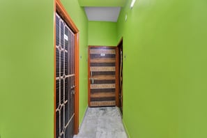 A narrow hallway with green walls and a wooden door labeled 'HP-6'. - Hotel O Palace (Kolkata)
