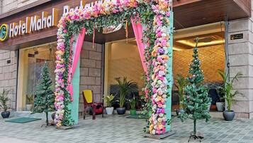 A hotel entrance with a floral archway, potted plants, and a CCTV surveillance sign.