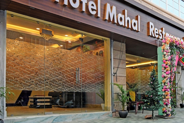 A hotel entrance with a large glass facade, a chandelier, and a floral decoration. - Collection O Mahal (Kolkata)