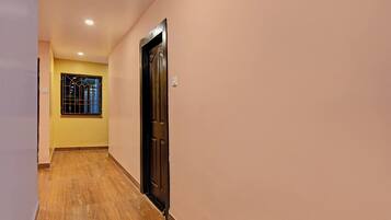 A hallway with a wooden floor, a door, and a window with bars.